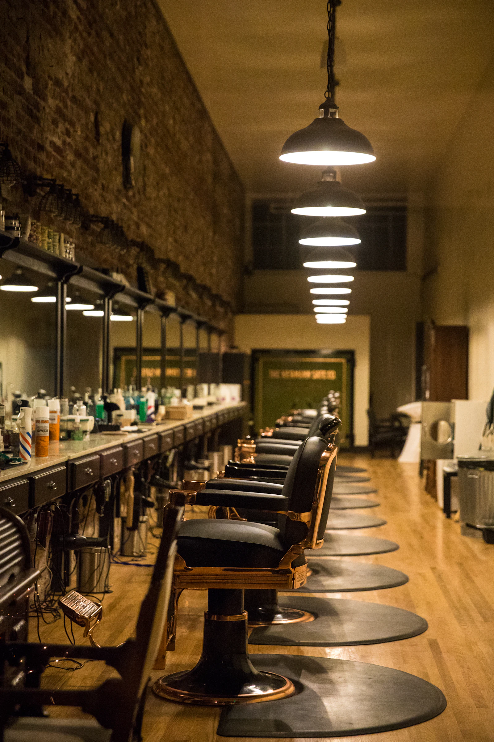 A long row of barber chairs under pendant lights