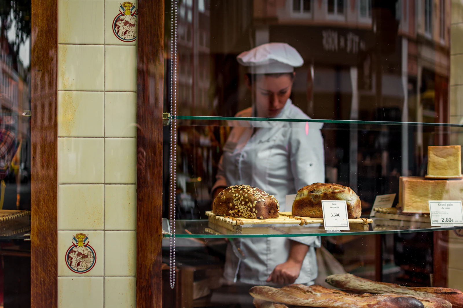 A baker in whites behind the glass counter